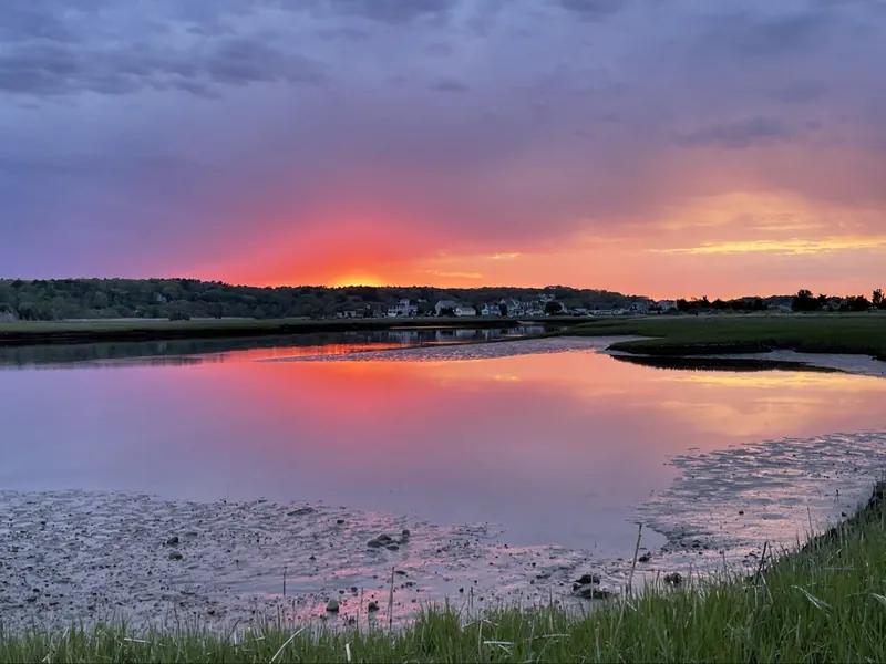 Sunset over the South River salt marsh in Marshfield, MA — pink sky reflected in still water at low tide